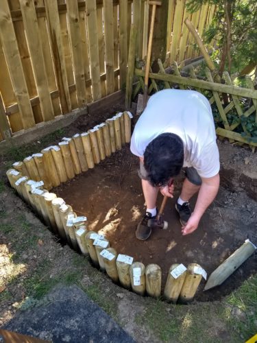 Sandkasten bauen mit Rundholzpalisaden